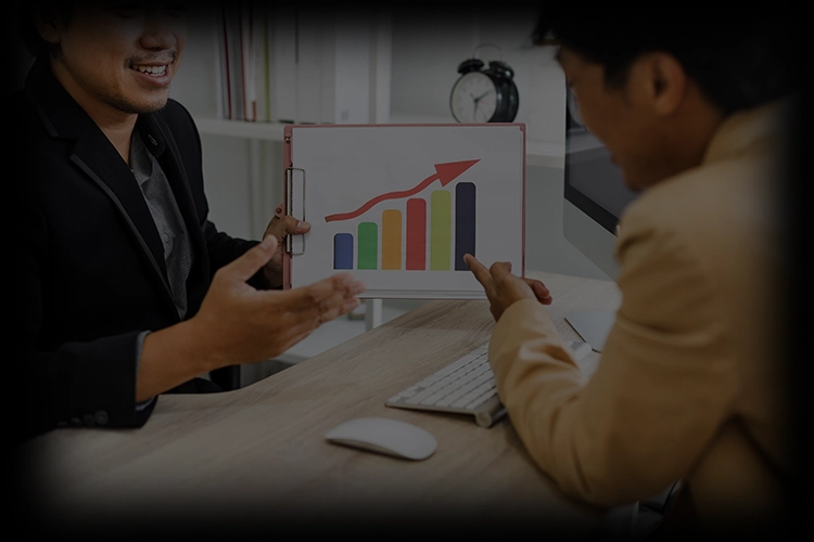 Two people reviewing a printed bar chart together