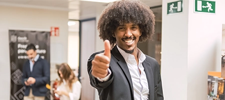 Man in a suit giving a thumbs up in an office