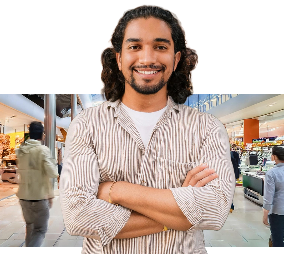 Smiling man with his arms crossed standing in a shopping mall